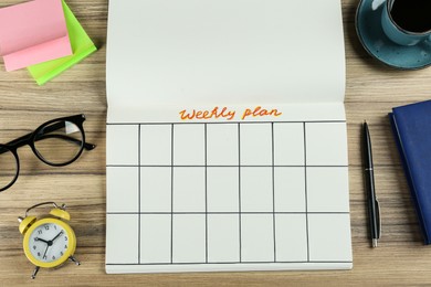 Photo of Flat lay composition of notebook with weekly plan on wooden table