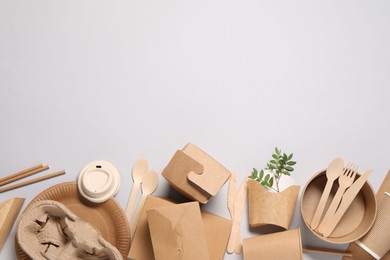 Photo of Eco friendly food packaging. Paper containers, tableware and green twigs on light grey background, flat lay. Space for text