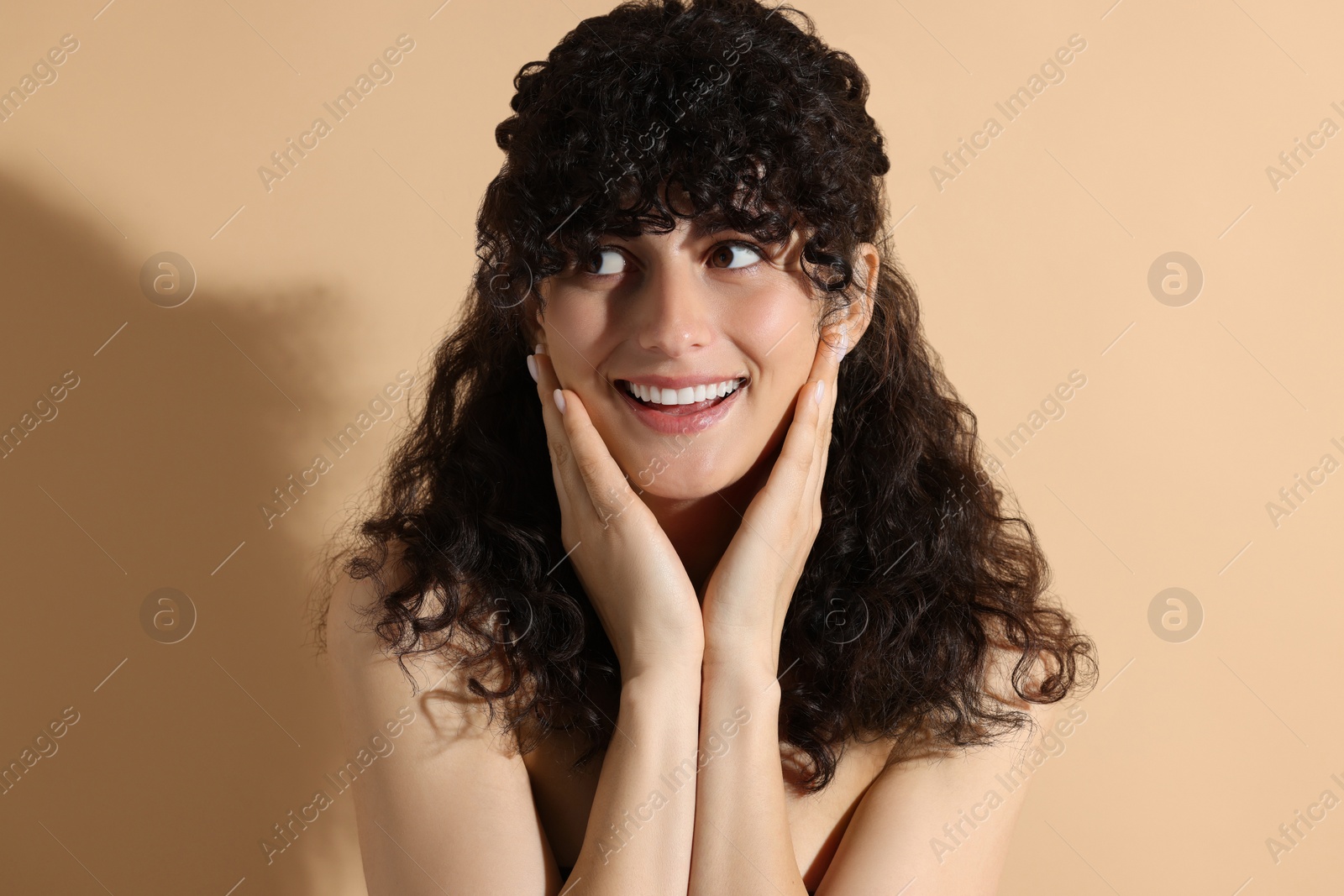 Photo of Portrait of beautiful young woman in sunlight on beige background