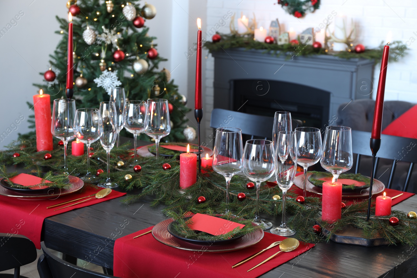 Photo of Elegant Christmas table setting with dishware and burning candles in festively decorated room