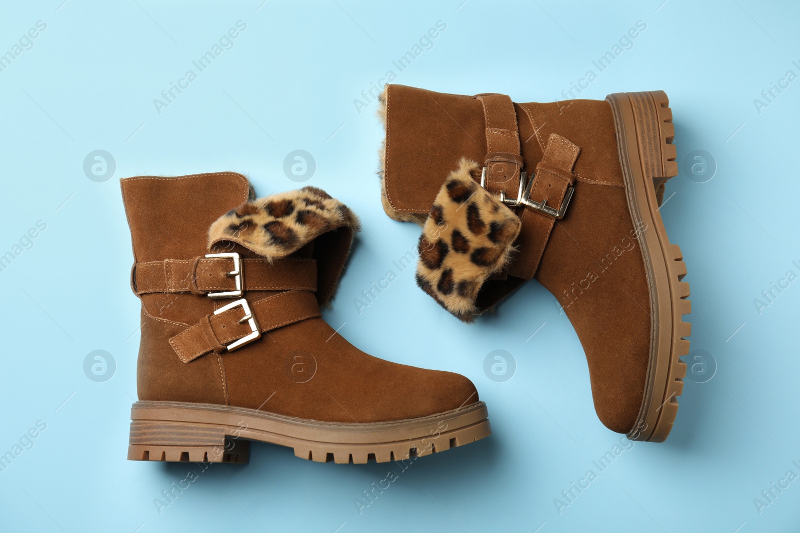 Photo of Stylish brown boots on light blue background, top view