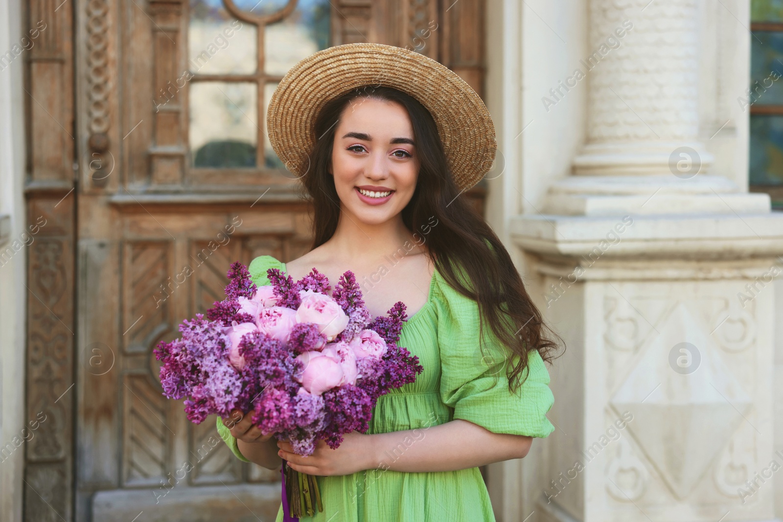 Photo of Beautiful woman with bouquet of spring flowers near building outdoors