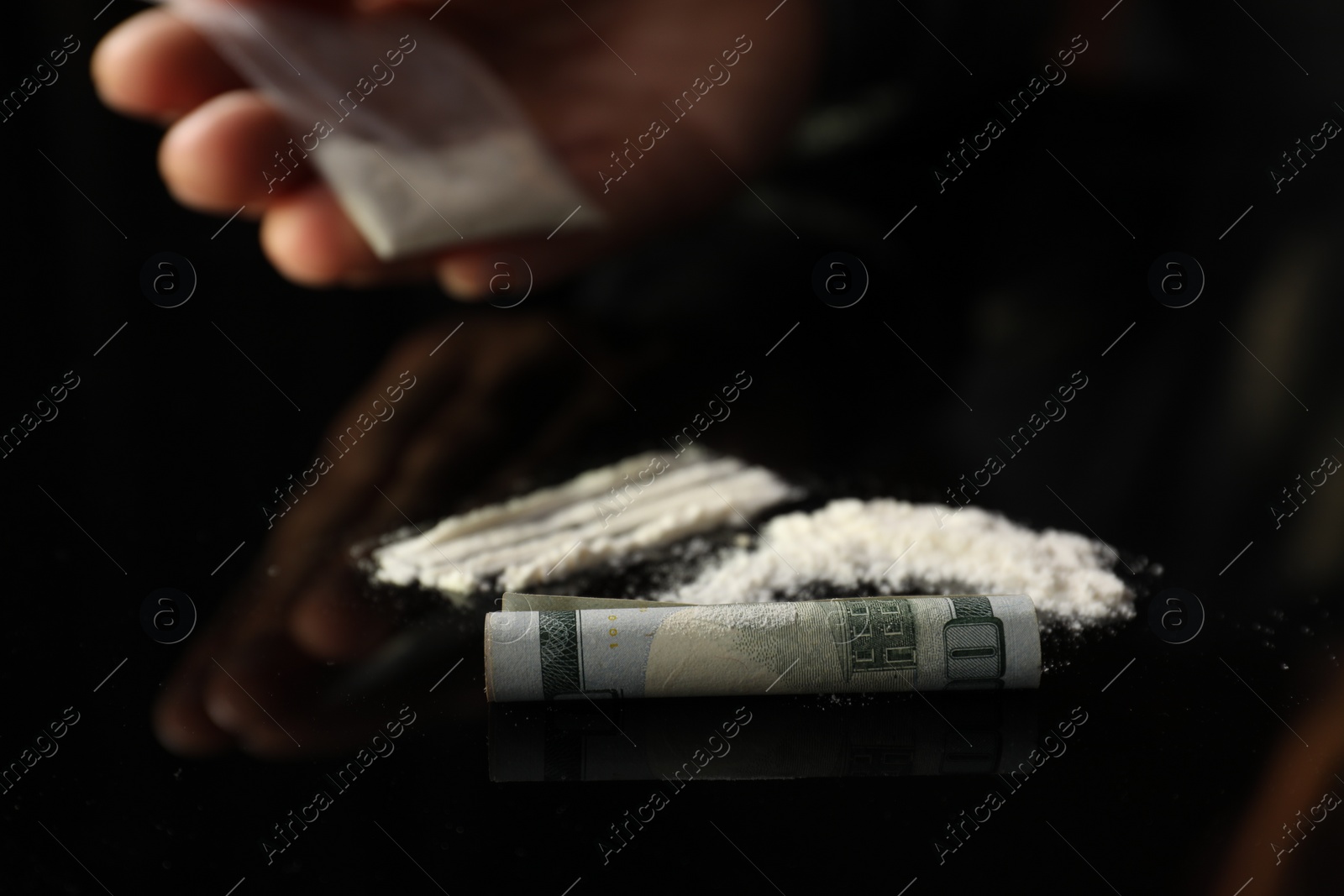 Photo of Drug addiction. Man with cocaine and rolled dollar banknote at black table, selective focus