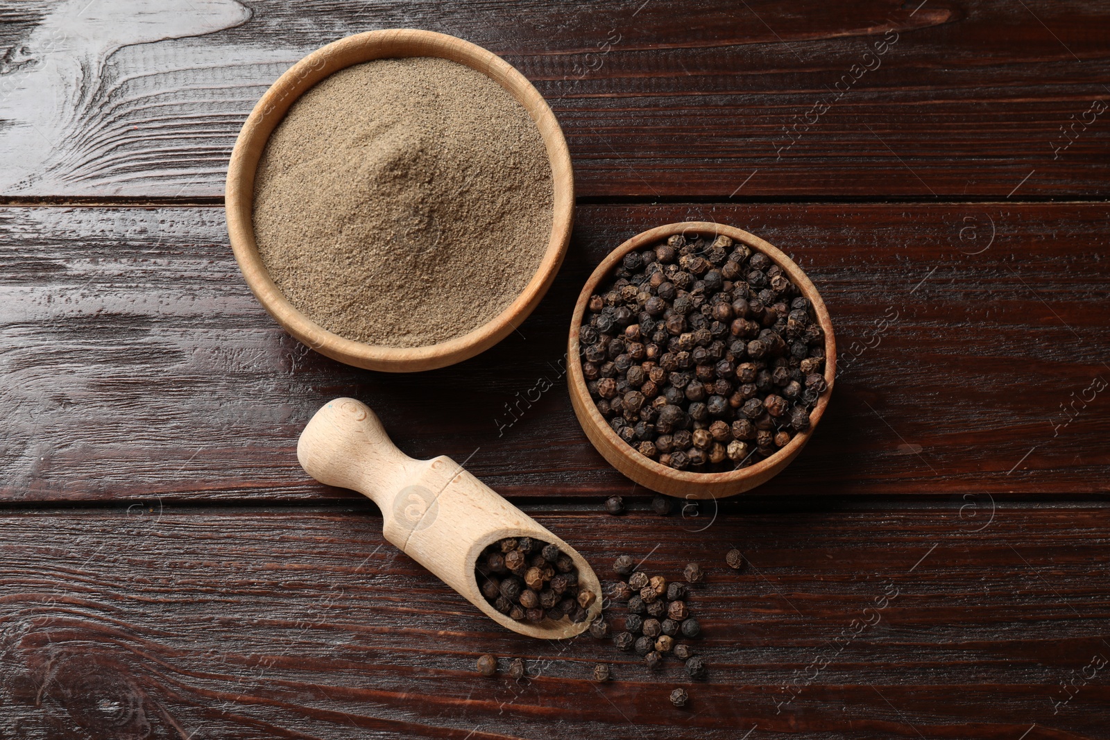 Photo of Aromatic spice. Ground and whole black pepper on wooden table, flat lay