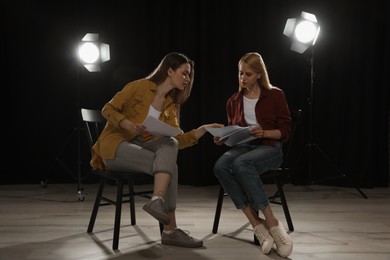 Photo of Professional actresses reading their scripts during rehearsal in theatre