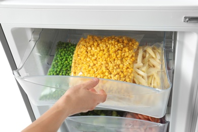 Woman opening refrigerator drawer with frozen vegetables, closeup