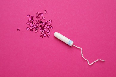 Photo of Tampon and sequins on pink background, flat lay. Menstrual hygiene product