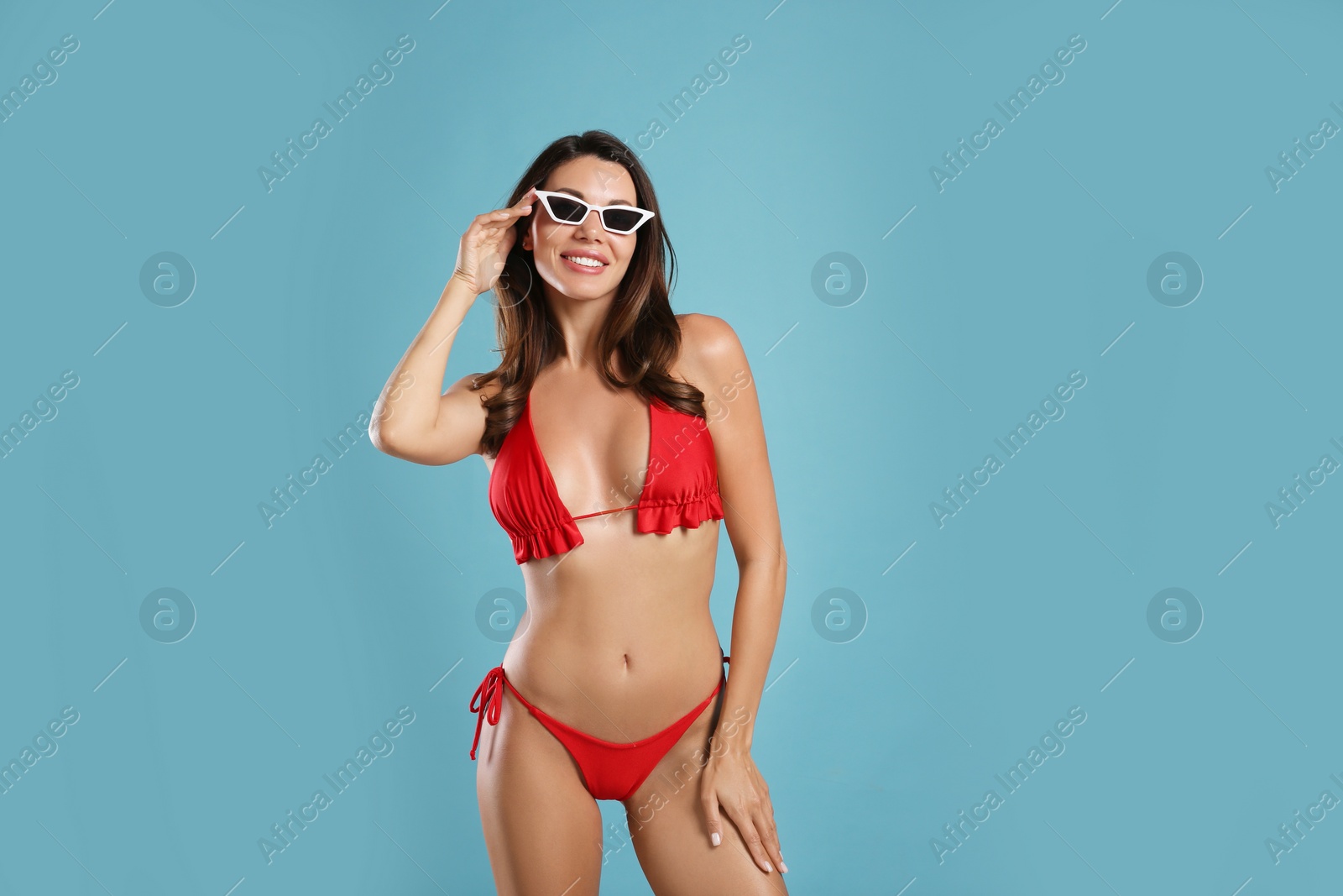 Photo of Beautiful woman in stylish bikini and sunglasses on blue background. Space for text