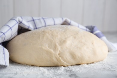 Photo of Fresh yeast dough with flour on white marble table, closeup