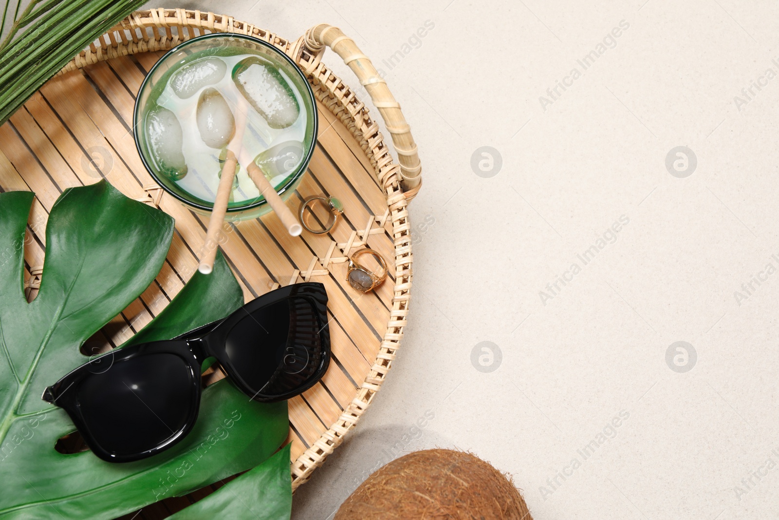 Photo of Flat lay composition with stylish sunglasses and refreshing drink on sand. Space for text