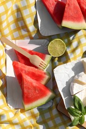 Photo of Delicious watermelon, cheese and lime on picnic blanket, flat lay