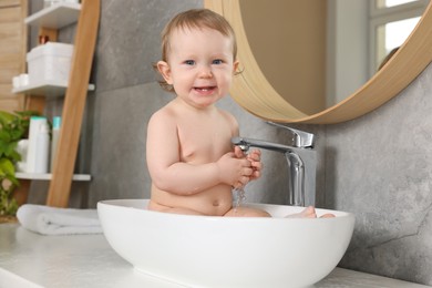 Photo of Cute little baby bathing in sink at home