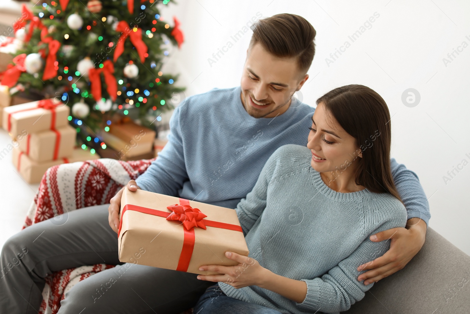 Photo of Young couple with Christmas gift at home