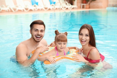 Photo of Happy family with inflatable ring in swimming pool