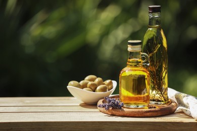 Photo of Different cooking oils and ingredients on wooden table against blurred green background, space for text