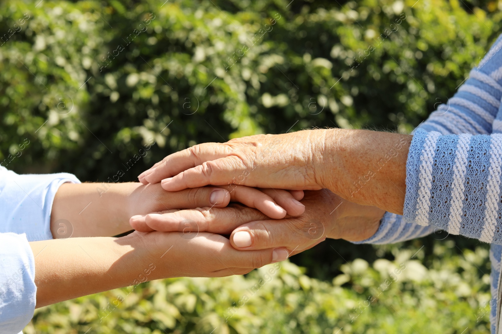 Photo of Helping hands on blurred background, closeup. Elderly care concept