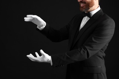 Photo of Magician holding something on black background, closeup