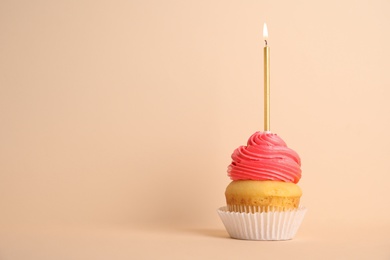 Birthday cupcake with candle on beige background, space for text