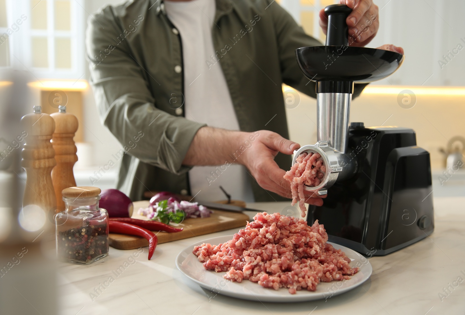 Photo of Man using modern meat grinder in kitchen, closeup