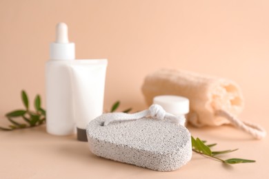 Photo of Pumice stone, cosmetic products and loofah on beige background