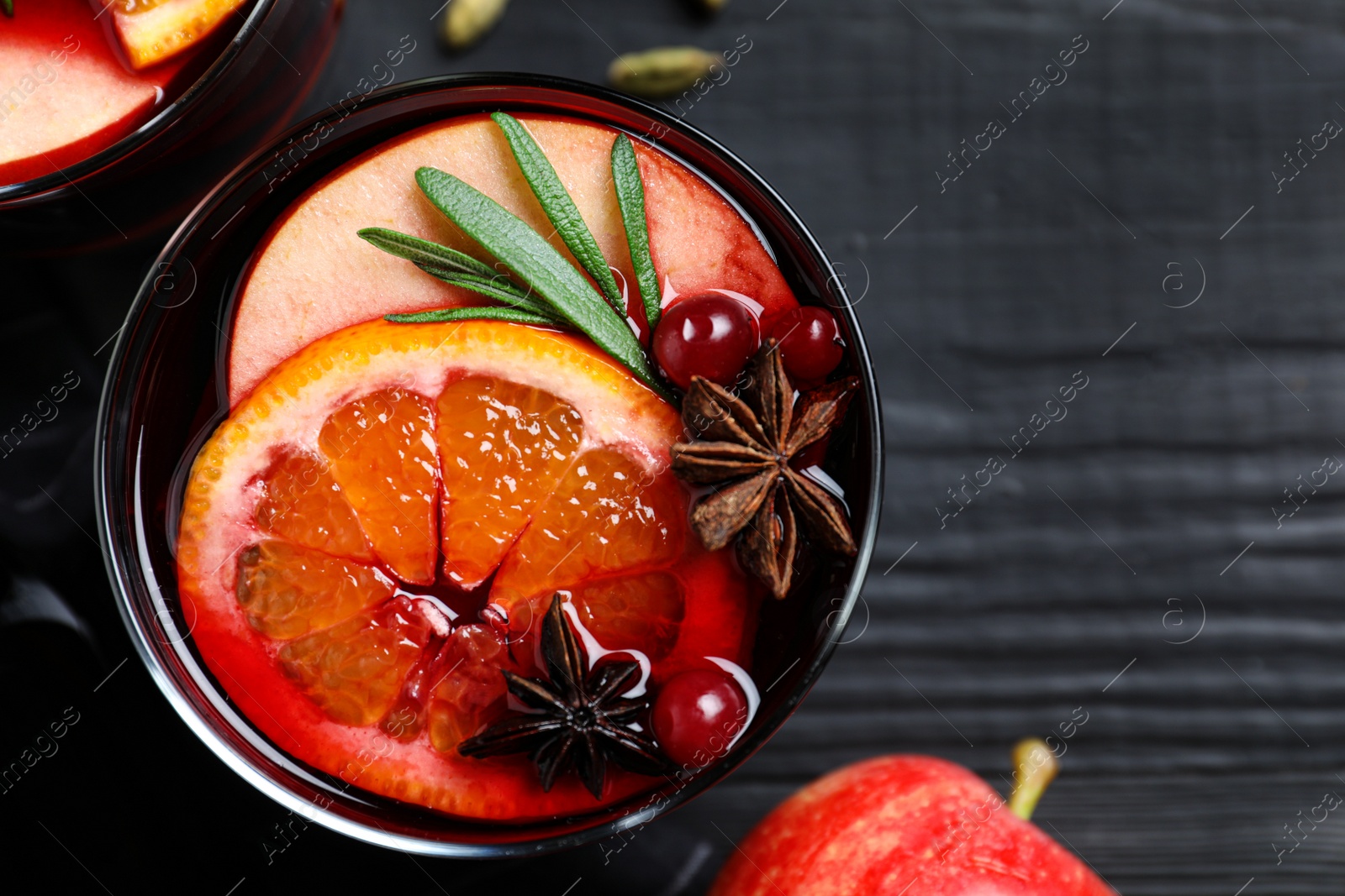 Photo of Cup of tasty mulled wine on black wooden table, flat lay