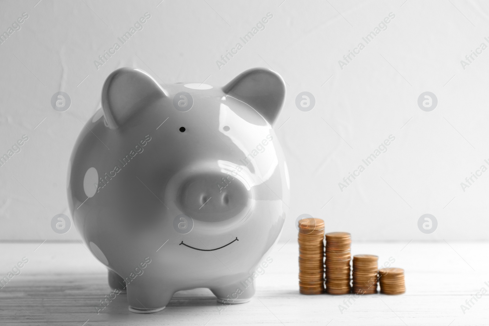 Photo of Piggy bank and coins on table against light background