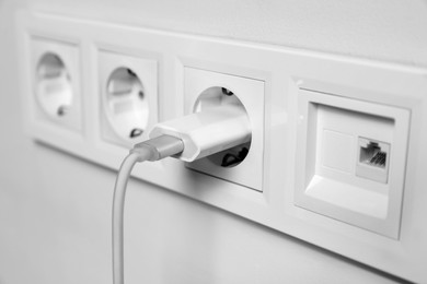 Photo of Charger adapter plugged in power socket indoors, closeup
