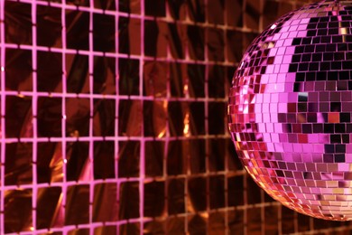 Photo of Shiny disco ball against foil party curtain under pink light, space for text