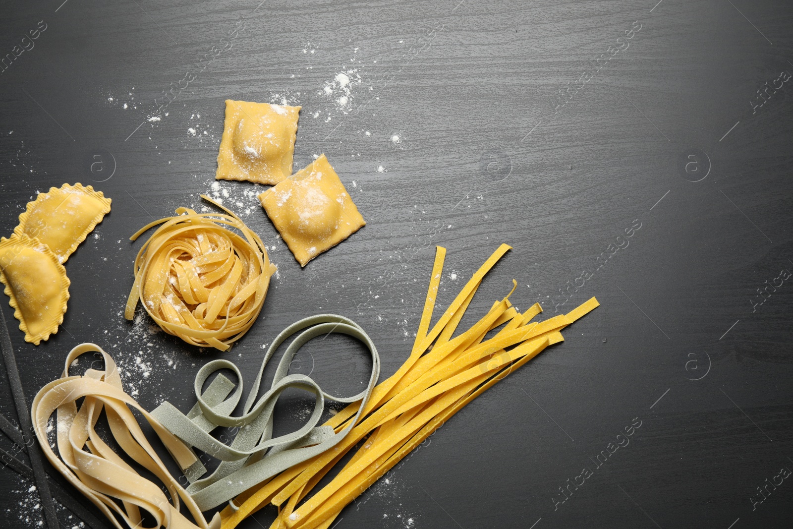 Photo of Flat lay composition with different types of pasta on black wooden table