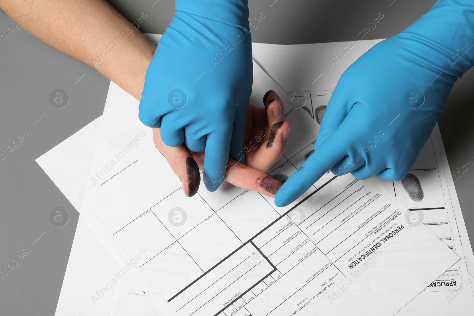 Photo of Investigator taking fingerprints of suspect on table, closeup