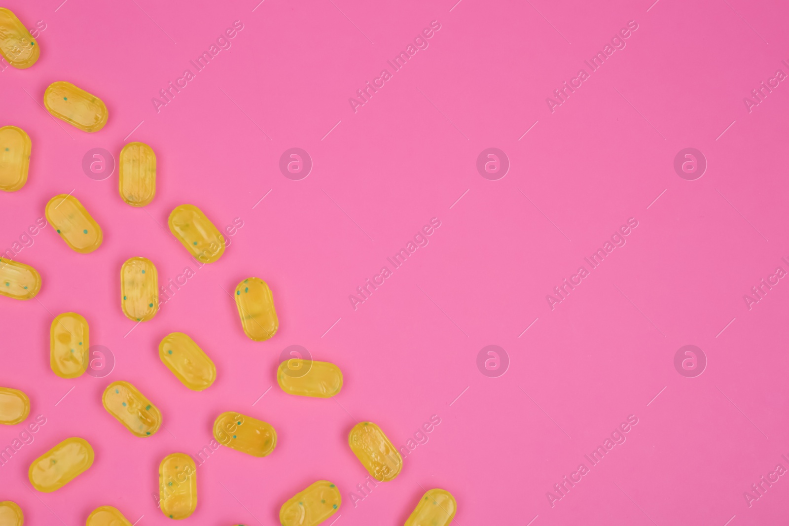 Photo of Many delicious lemon drops on pink background, flat lay. Space for text