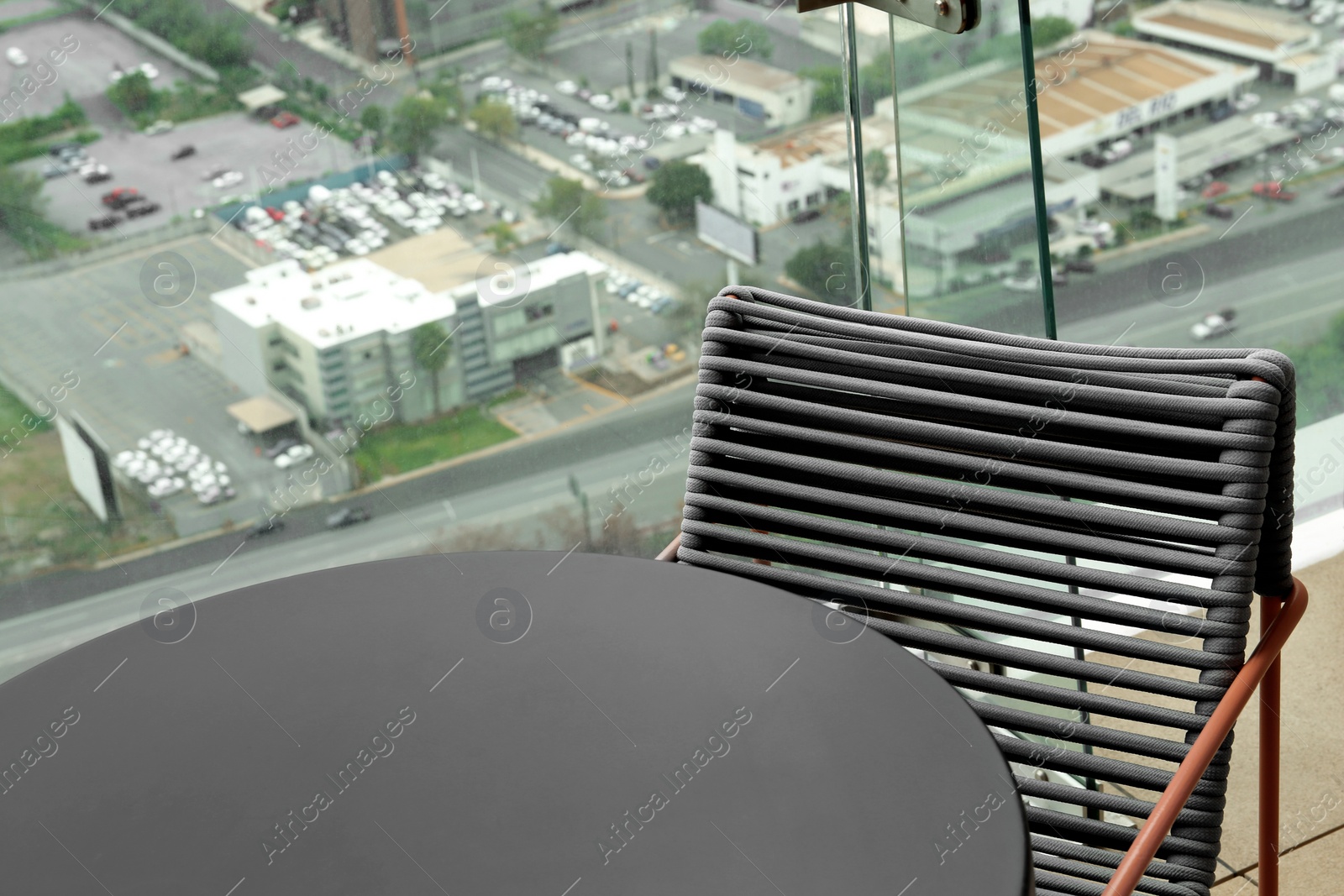 Photo of Coffee table and chair against picturesque landscape of city in cafe, closeup