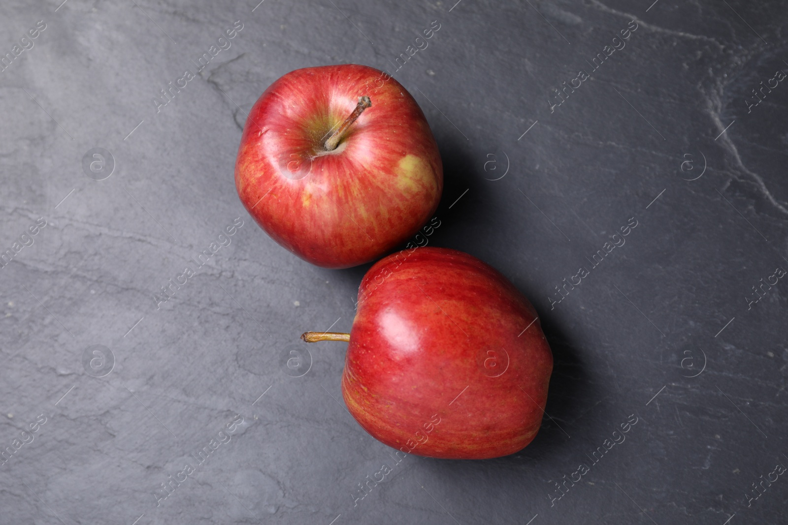 Photo of Ripe red apples on black textured table, flat lay