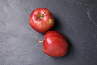 Photo of Ripe red apples on black textured table, flat lay