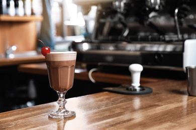 Photo of Glass of coffee drink with cherry on bar counter. Space for text