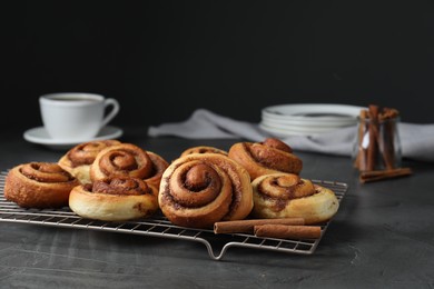 Tasty cinnamon rolls on black table, space for text