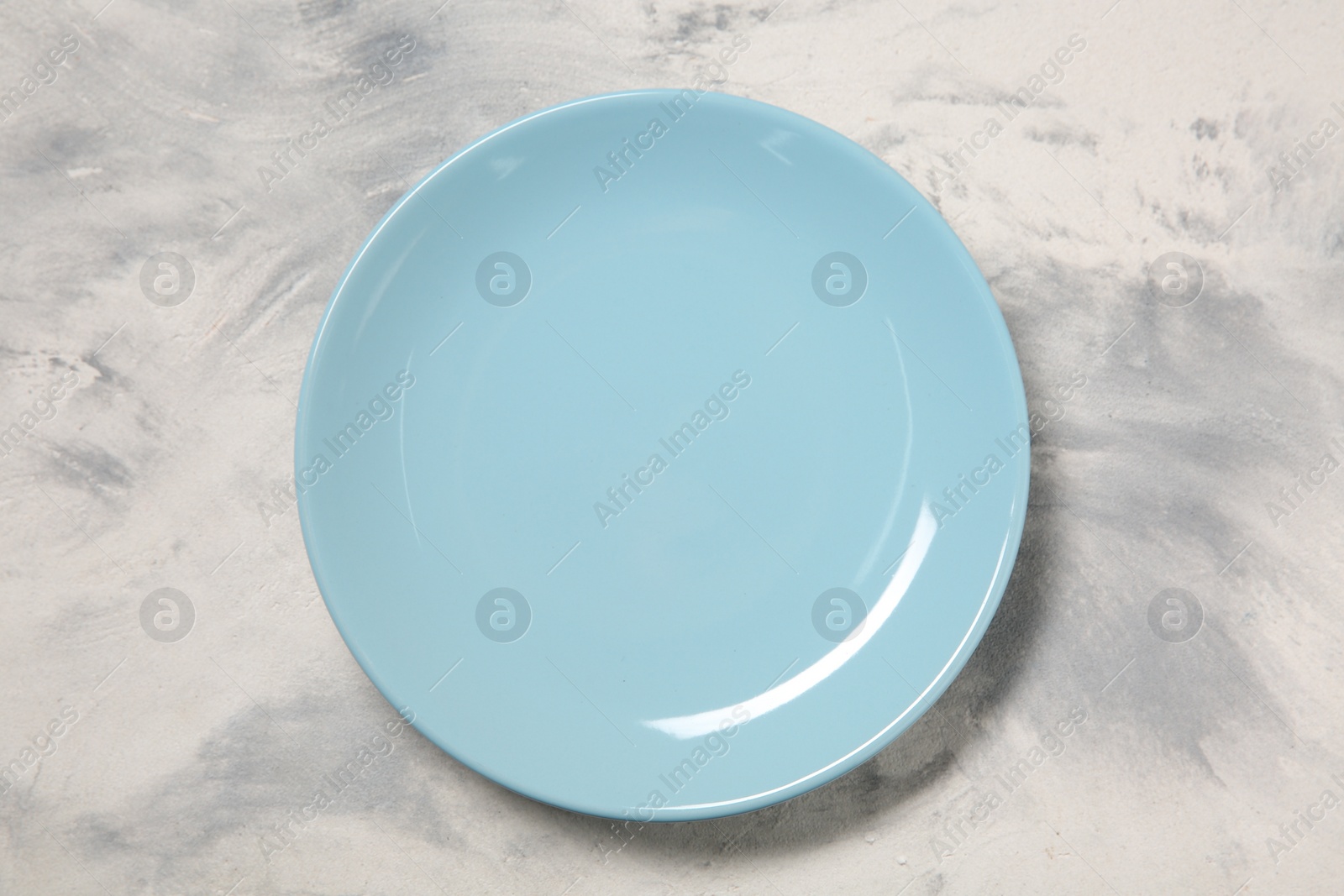 Photo of One ceramic plate on light textured table, top view