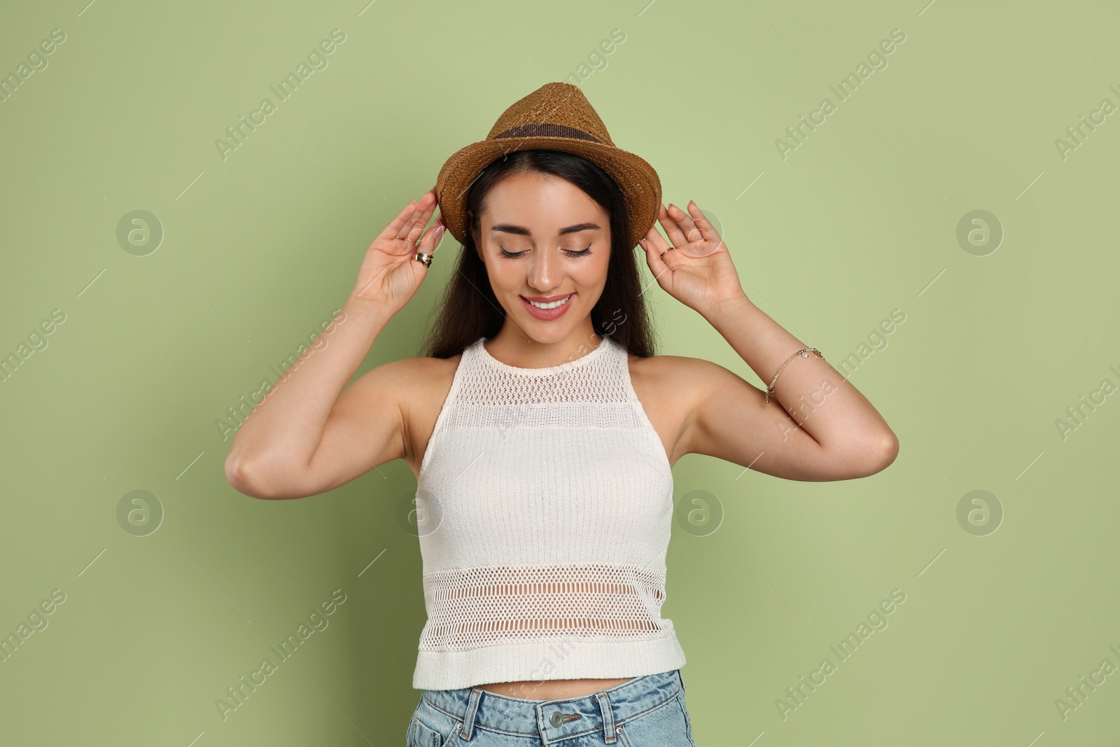 Photo of Beautiful young woman wearing straw hat on olive  background. Stylish headdress