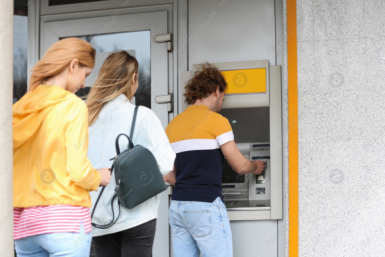 Photo of People standing in queue to cash machine outdoors