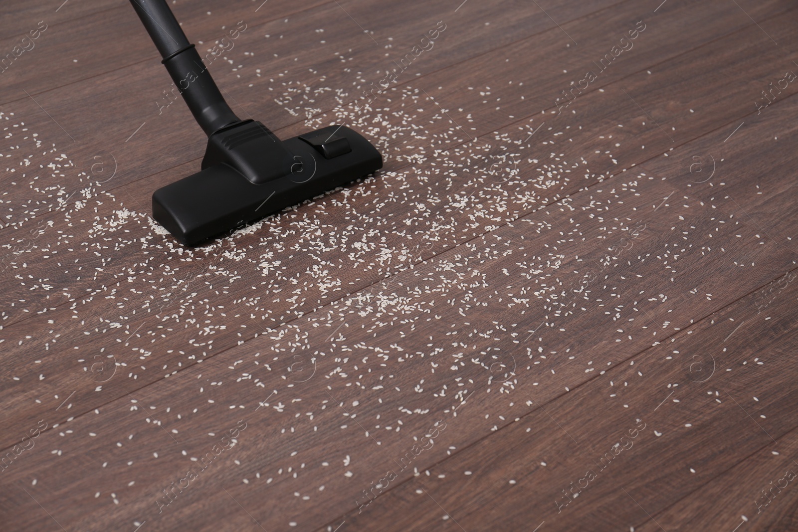 Photo of Vacuuming scattered rice from wooden floor. Space for text