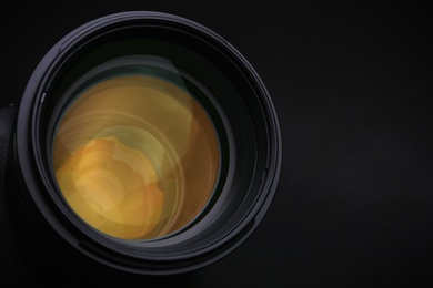 Photo of Modern camera lens on black background, closeup. Space for text