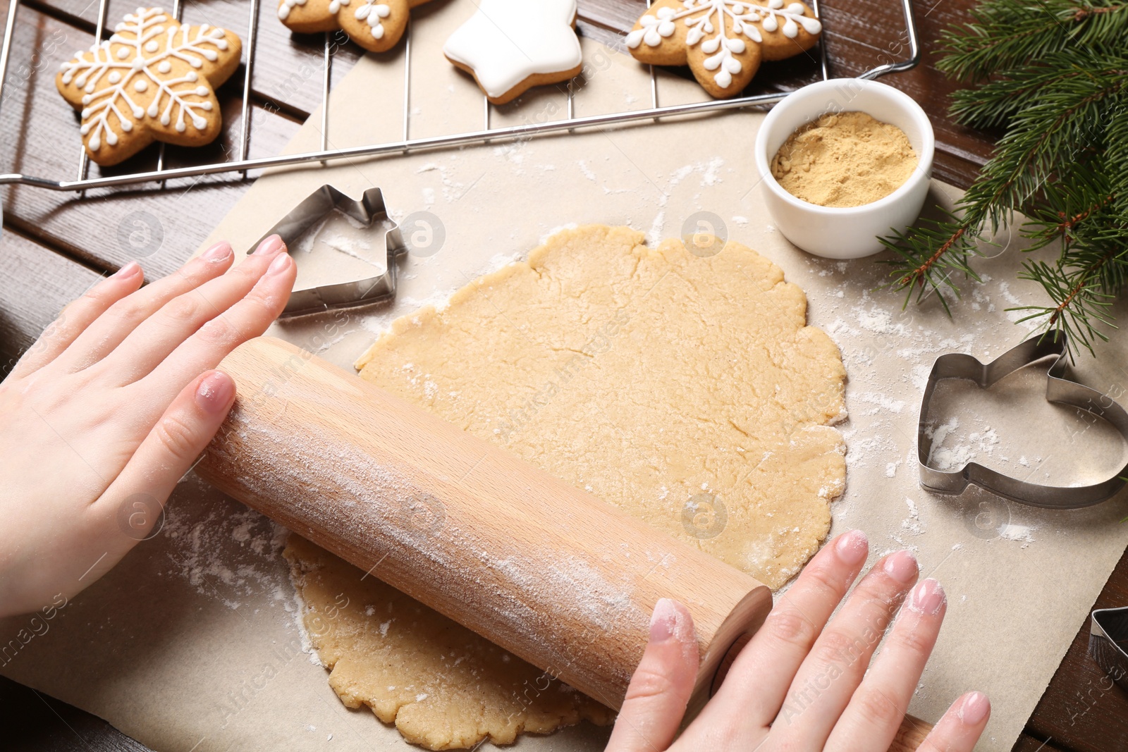 Photo of Making Christmas cookies. Woman rolling raw dough at wooden table, closeup