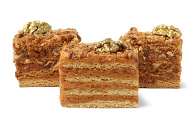 Photo of Pieces of layered honey cake with walnuts on white background