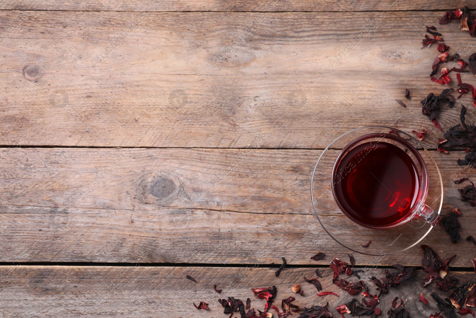 Photo of Delicious hibiscus tea and dry flowers on wooden table, flat lay. Space for text