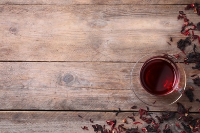 Photo of Delicious hibiscus tea and dry flowers on wooden table, flat lay. Space for text