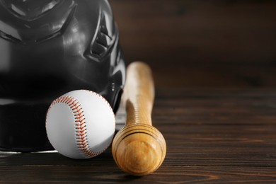 Photo of Baseball bat, ball and batting helmet on wooden table, closeup. Space for text