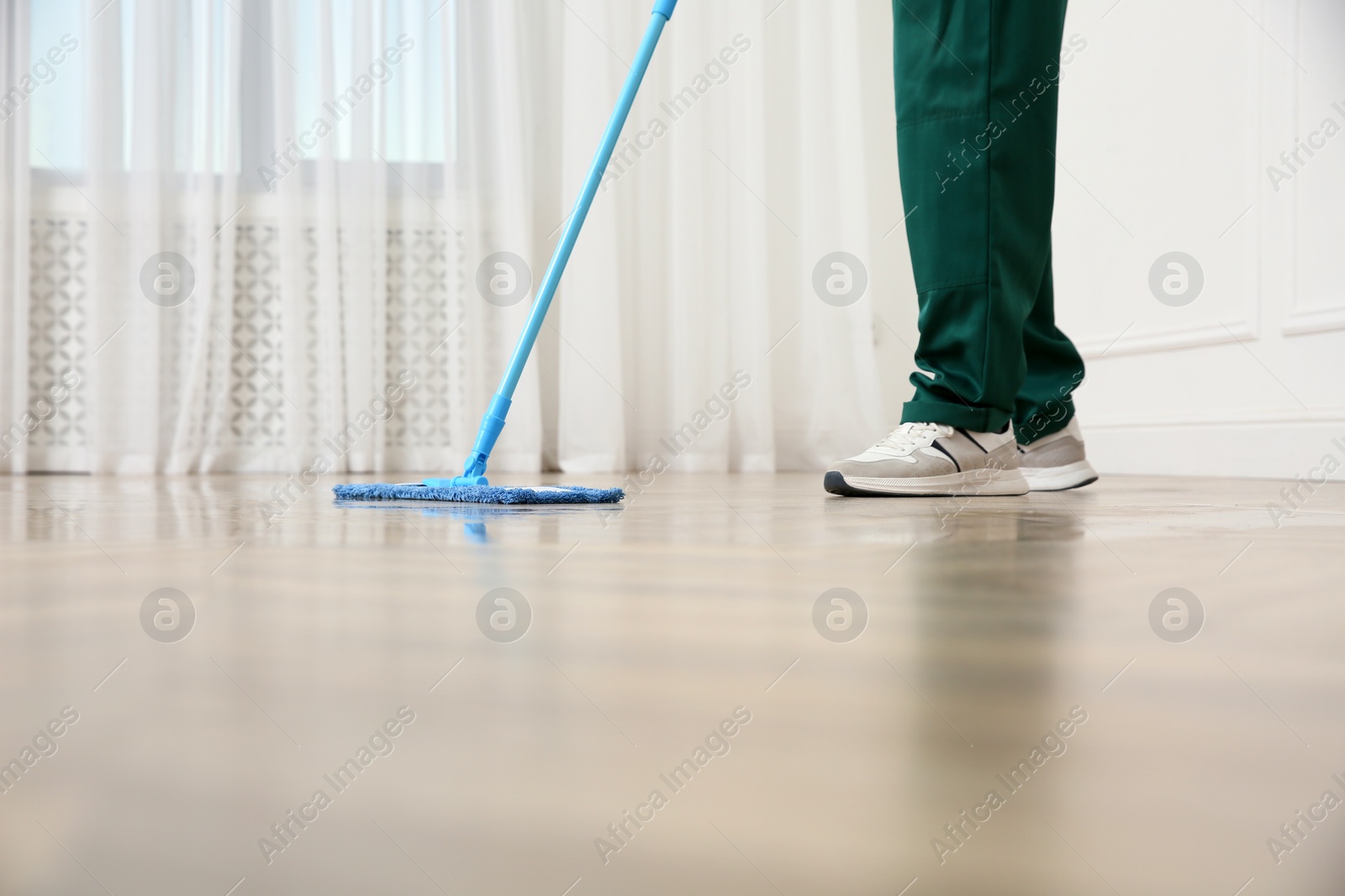 Photo of Professional janitor cleaning parquet floor with mop indoors, closeup