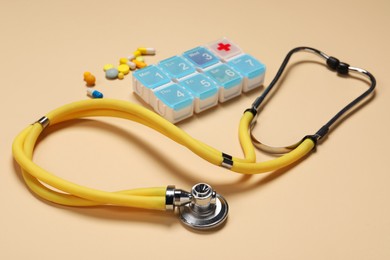 Photo of Stethoscope and pills on beige background, closeup. Medical tool