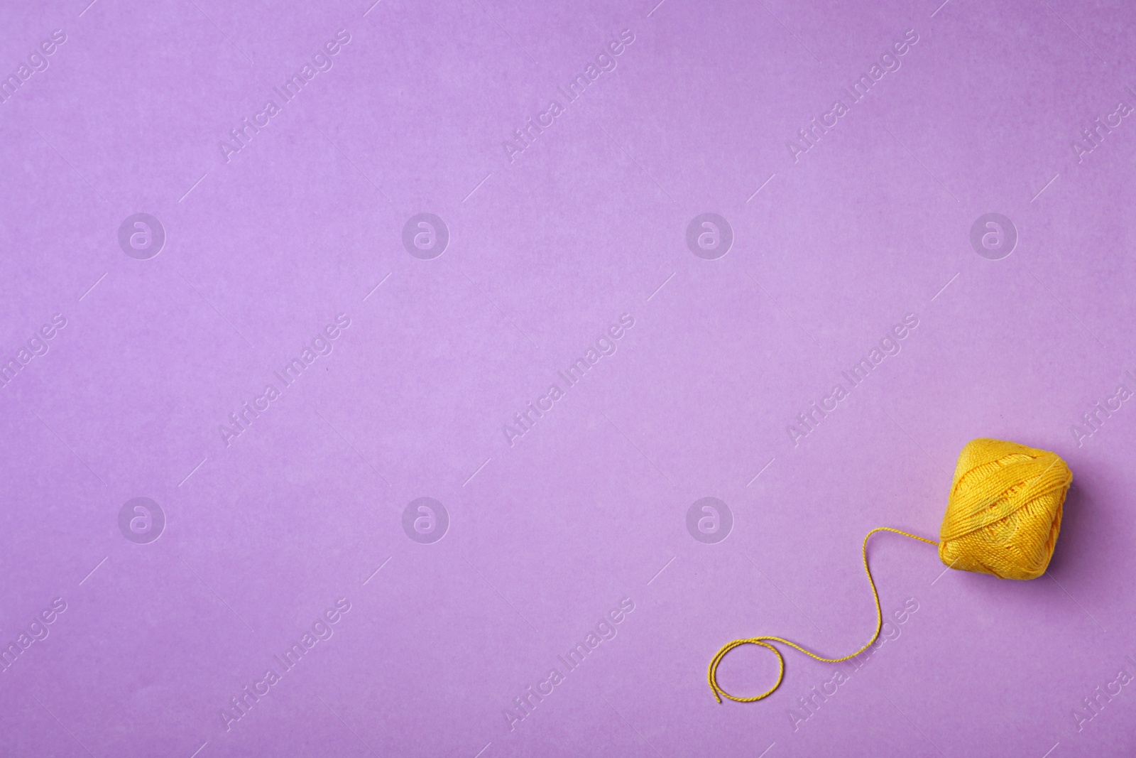 Photo of Yellow sewing thread on color background