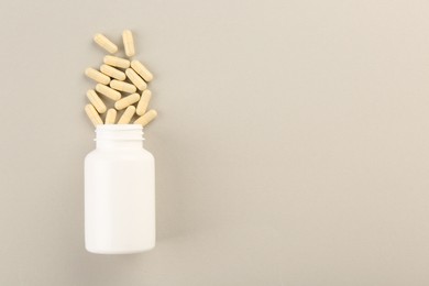 Bottle and vitamin capsules on light background, top view. Space for text